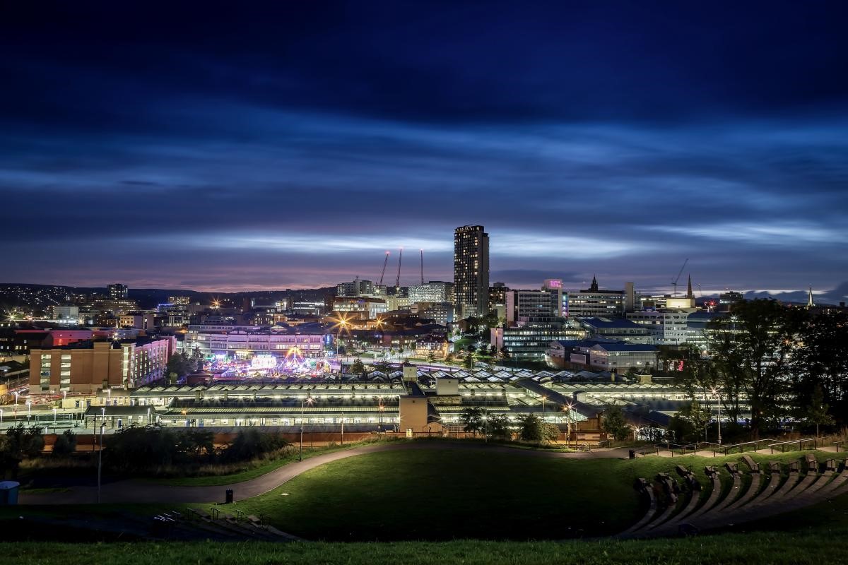 A nighttime view of Sheffield's skyline with a deep blue sky and the city centre lit up