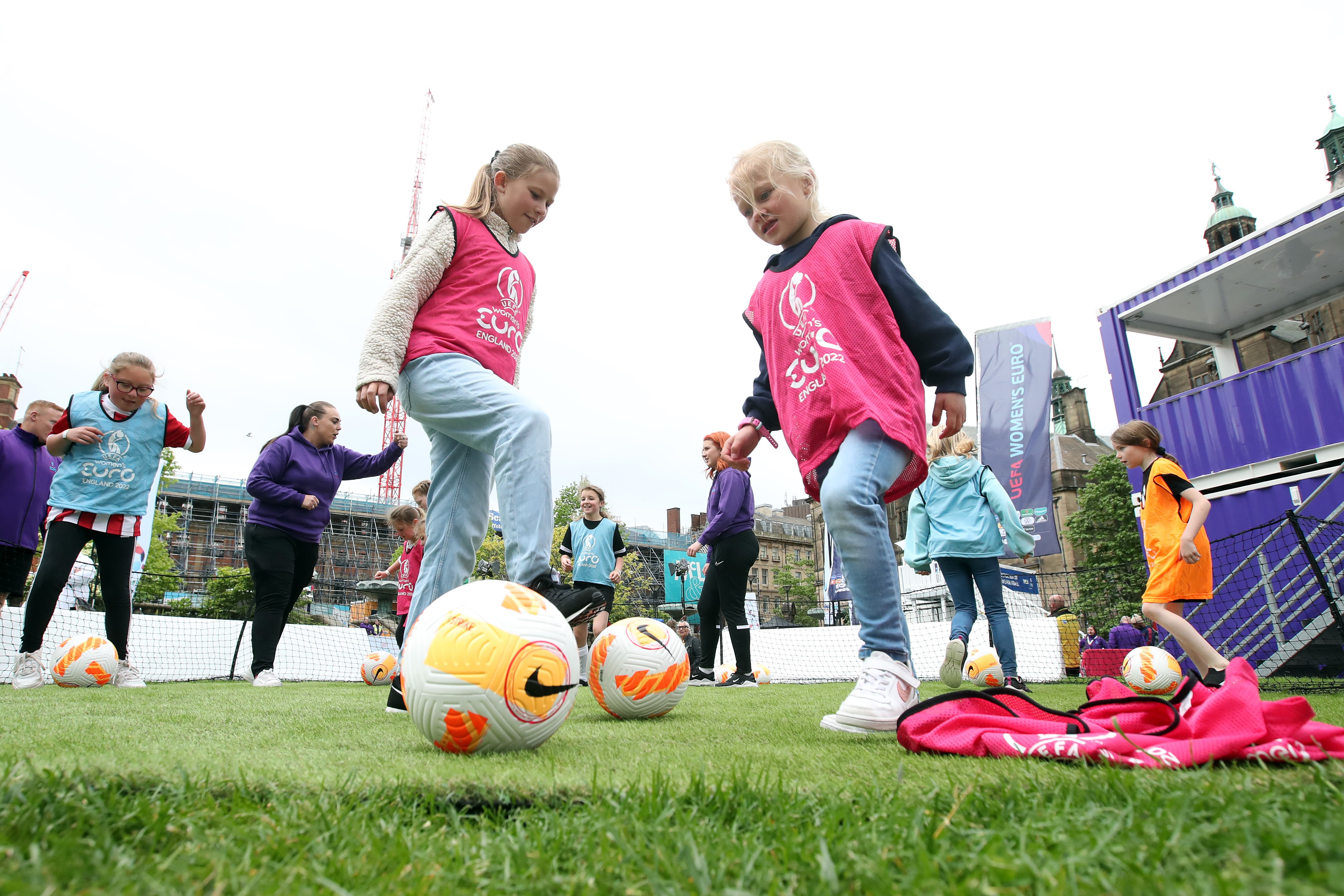 Girls playing football wearing UEFA Women's EURO 2022 bibs in the Peace Gardens in Sheffield