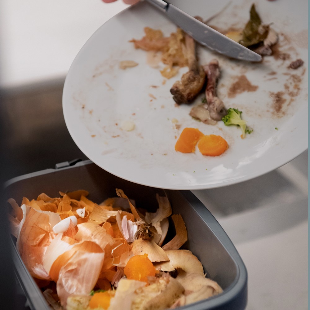 Food waste on white plate being scraped with knife