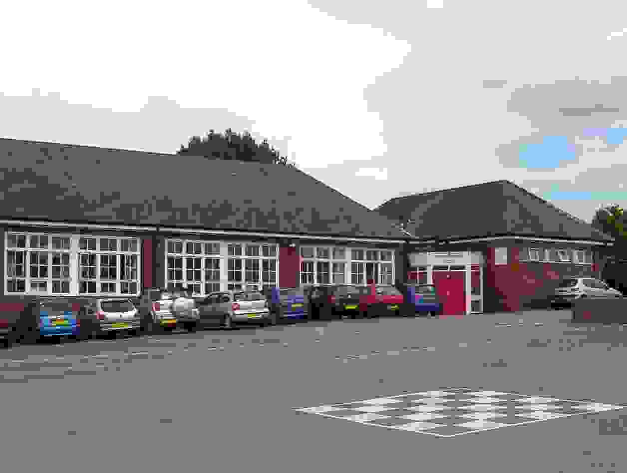 Pipworth School buildings with cars parked outside in the car park 