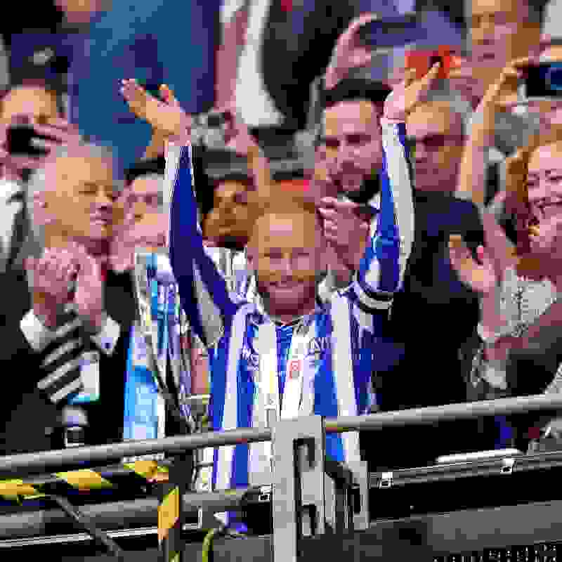 Sheffield Wednesday captain Barry Bannan raising his hands up in the stands, wearing a blue and white striped Sheffield Wednesday top