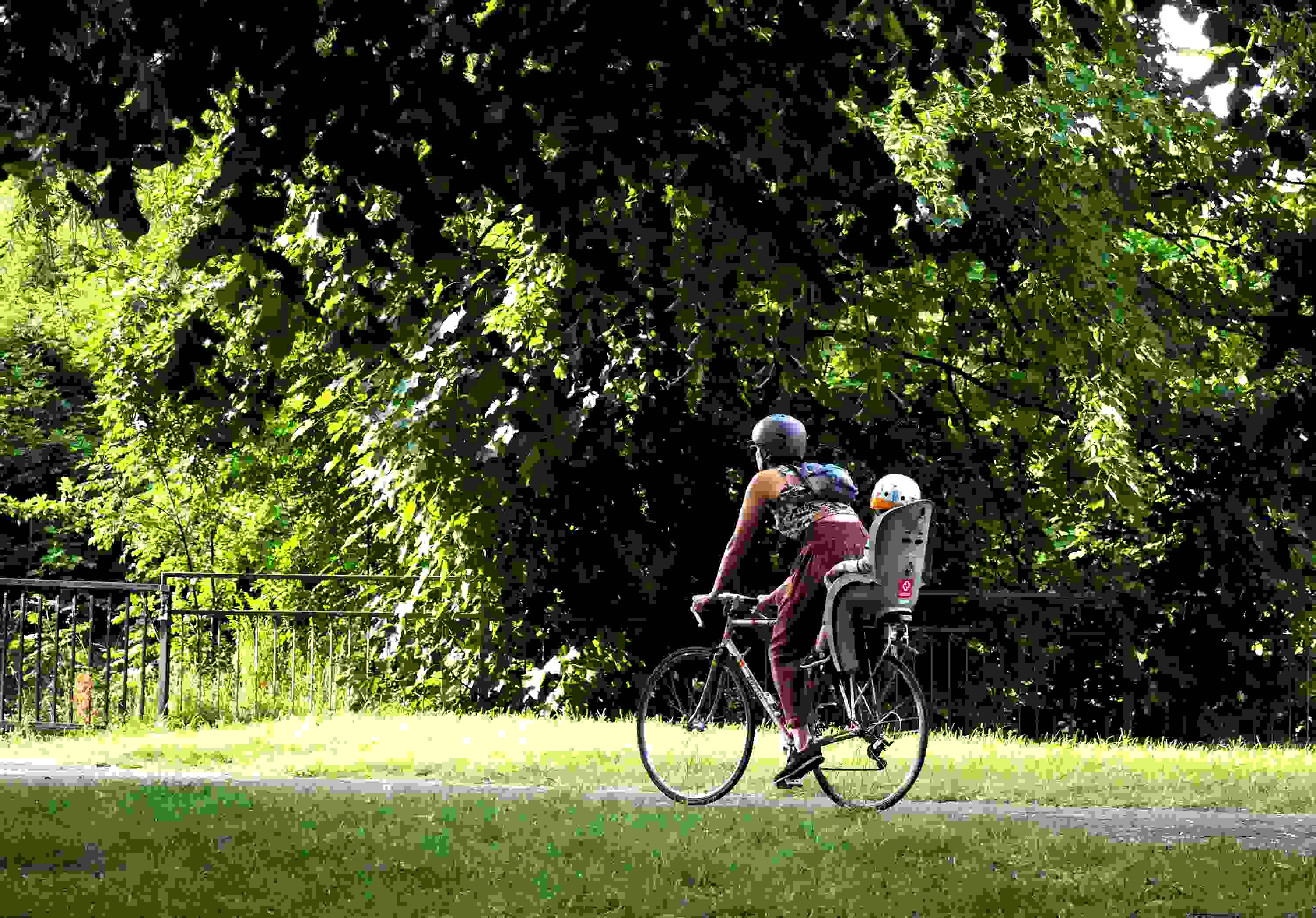 A mother and child cycle through a park