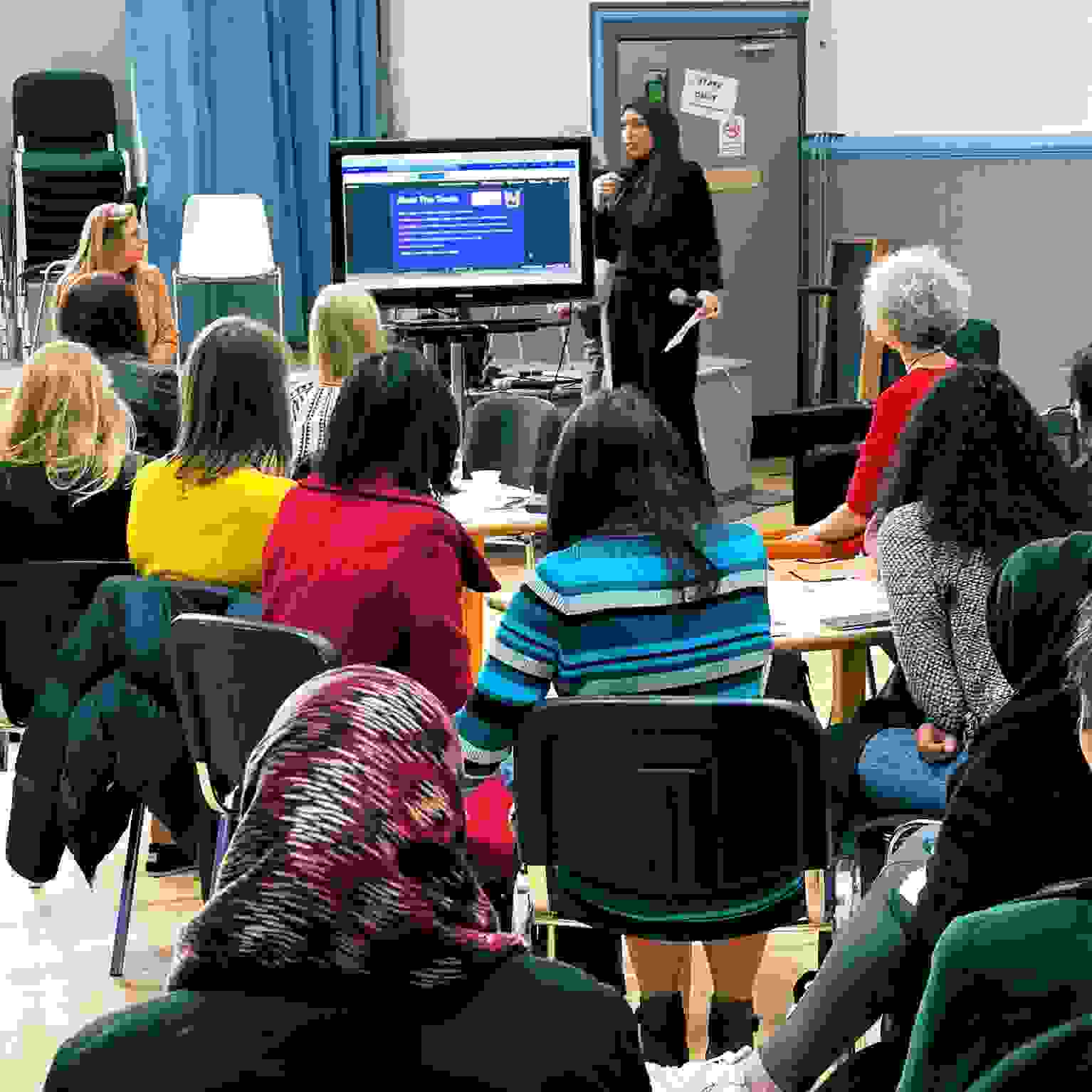 A group of people watching a presentation at a women’s networking event.
