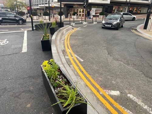 Temporary kerb on pavement lined with planters