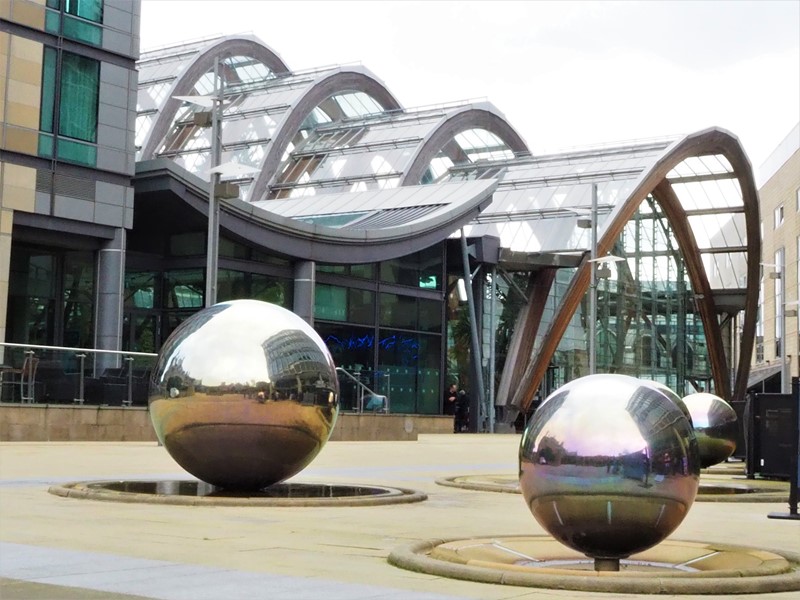 Building with steel sphere water feature in foreground