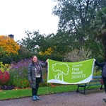 Cllr Mary Lea and Jill Thompson holding the green flag in the Sheffield Botanical Gardens with colourful plants in the background