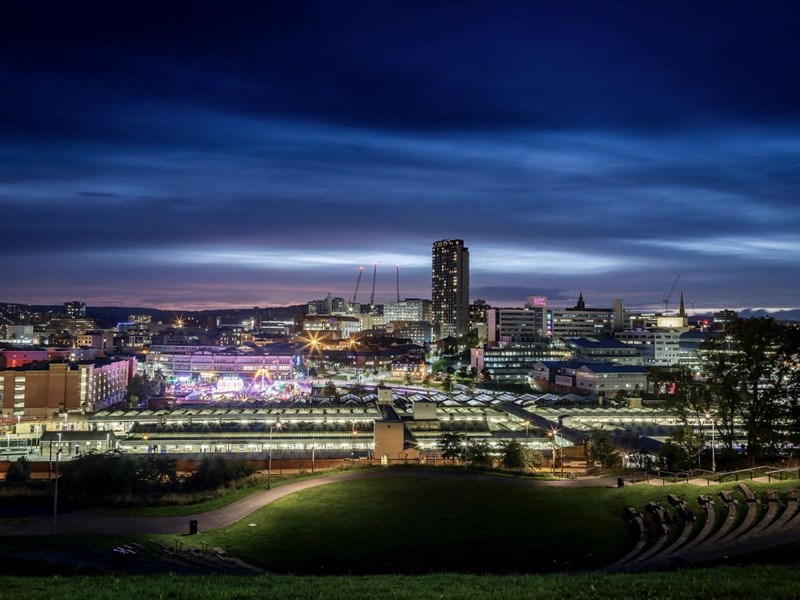 A nighttime view of Sheffield's skyline with a deep blue sky and the city centre lit up