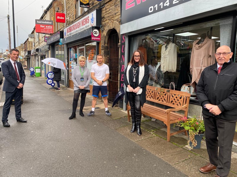 Four people stood distanced outside shop front on high street