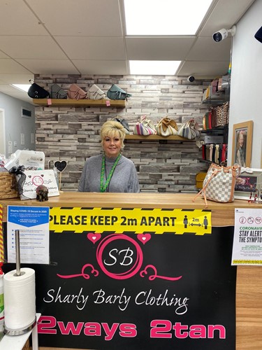 Woman stood behind counter with social distancing signage