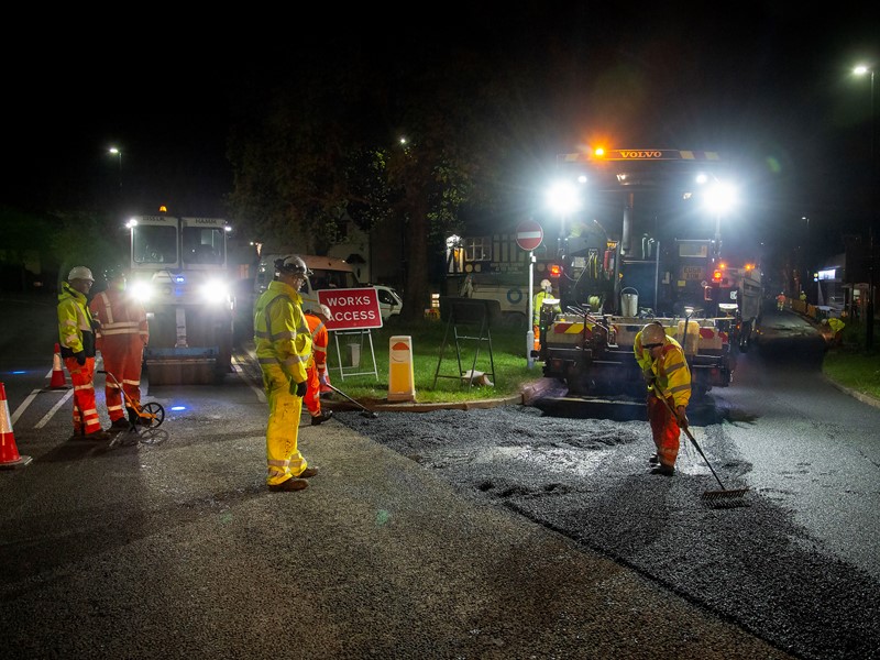 Roadworkers laying tarmac in the dark