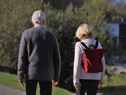 older man walking outdoors with woman