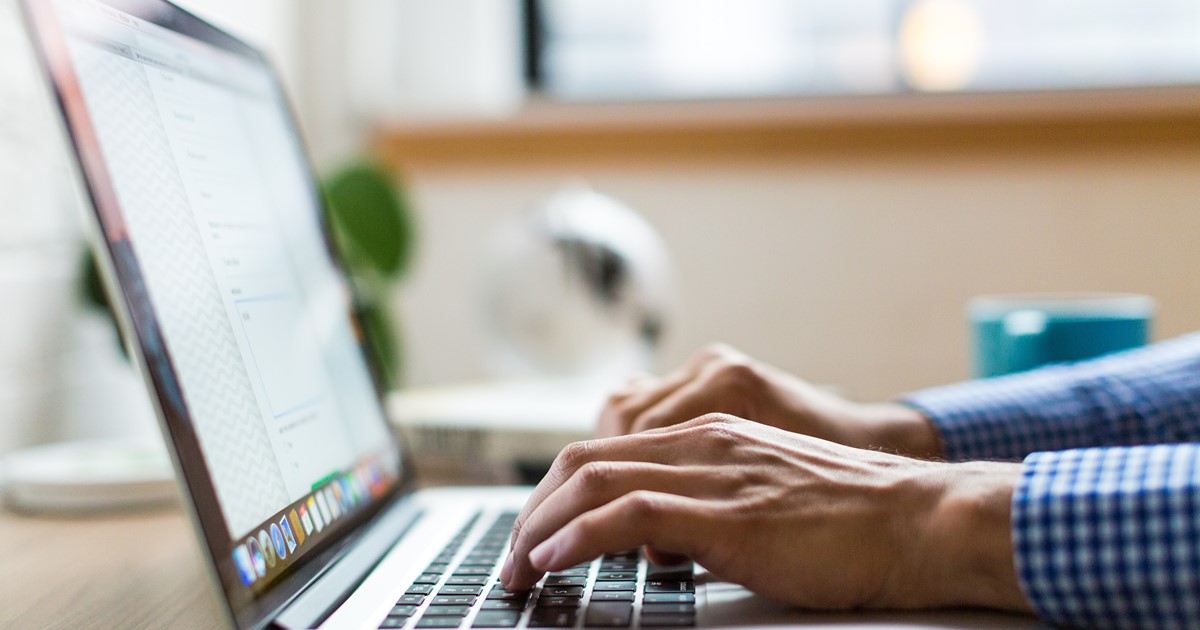 Hands typing on a laptop