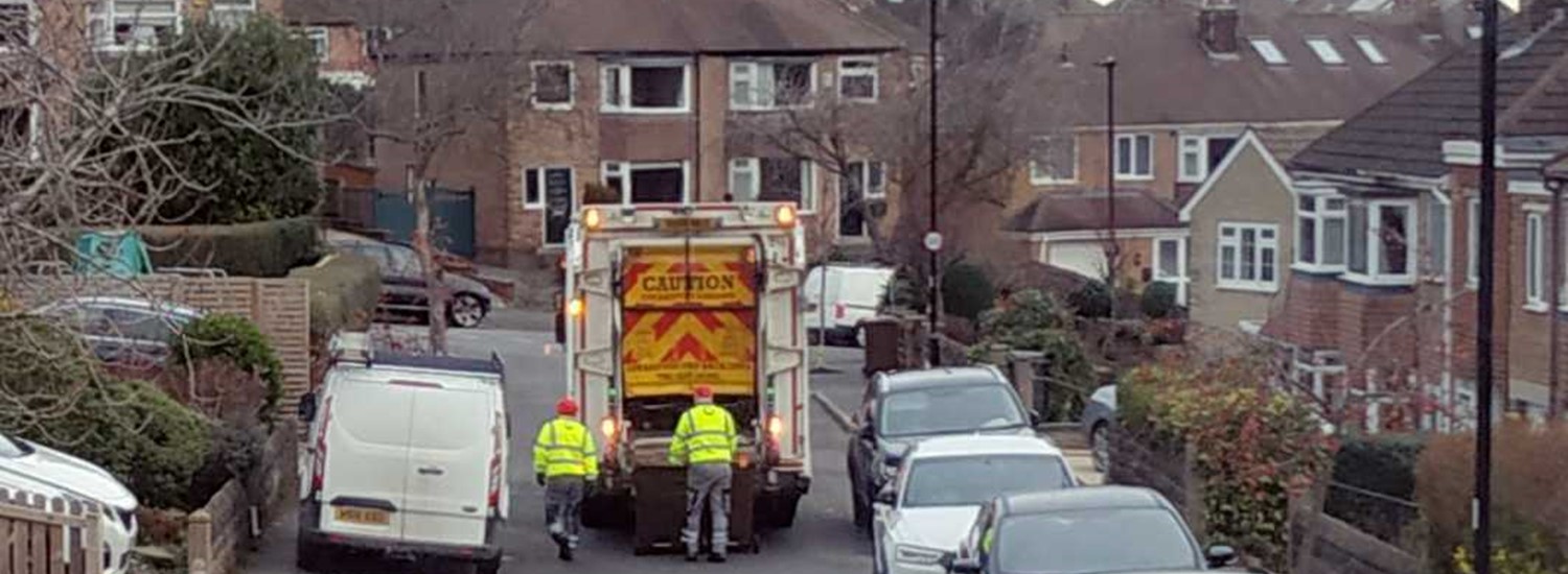 Street with bins being collected by bin lorry