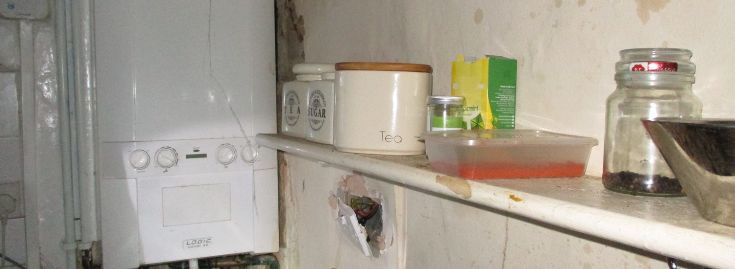 Part of a kitchen with damaged walls and poor conditions