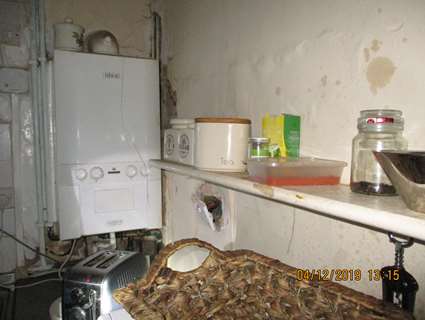 Part of a kitchen in disrepair with damaged walls