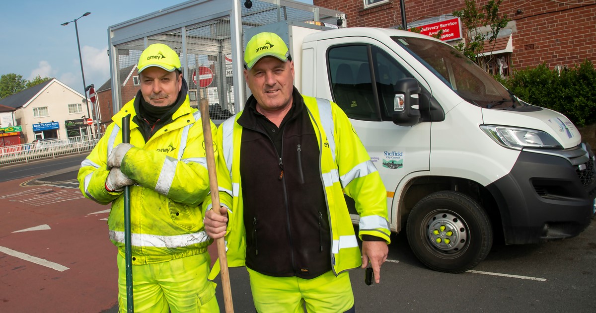 Two men in high visibility clothing standing in front of a white van
