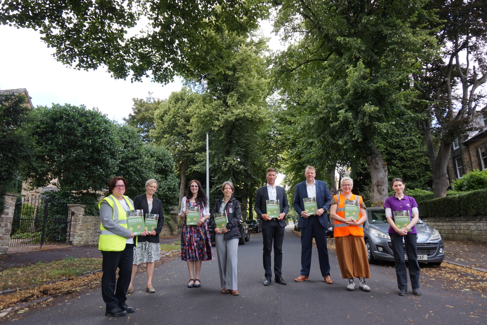 A group of people gather on a tree lined street