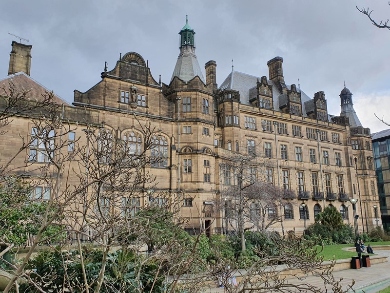 Sheffield Town Hall can be seen overlooking the Peace Gardens with trees in the foreground.