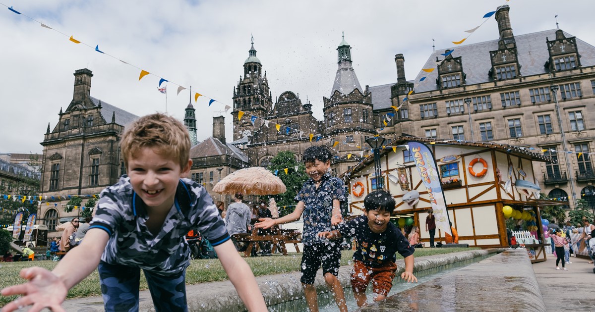Three young children play in the fountains outside Sheffield Town Hall