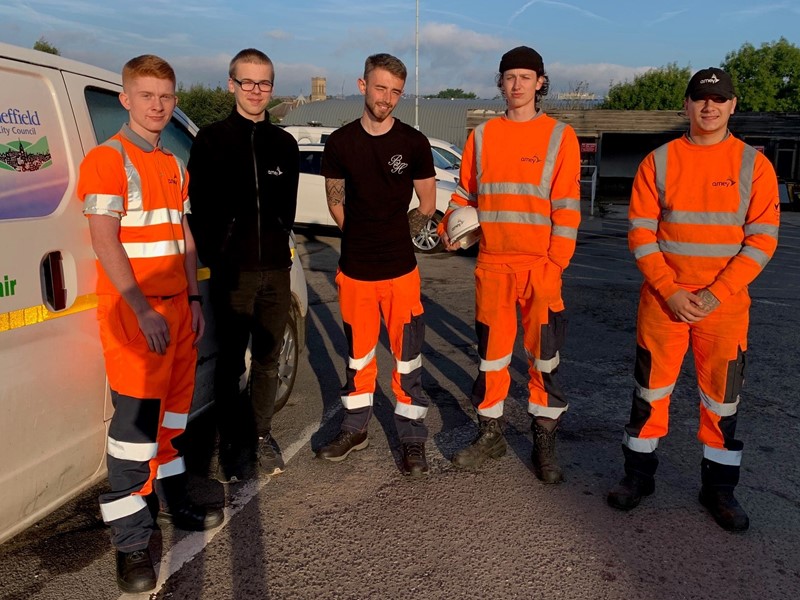 5 people in high visibility clothing stand next to white van