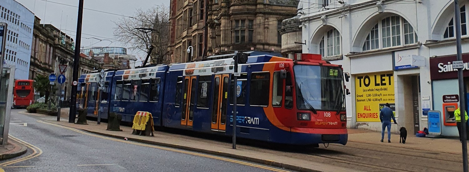 A red, blue and orange Supertram drives through Sheffield City Centre