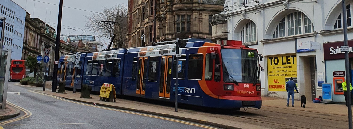 A red, blue and orange Supertram drives through Sheffield City Centre