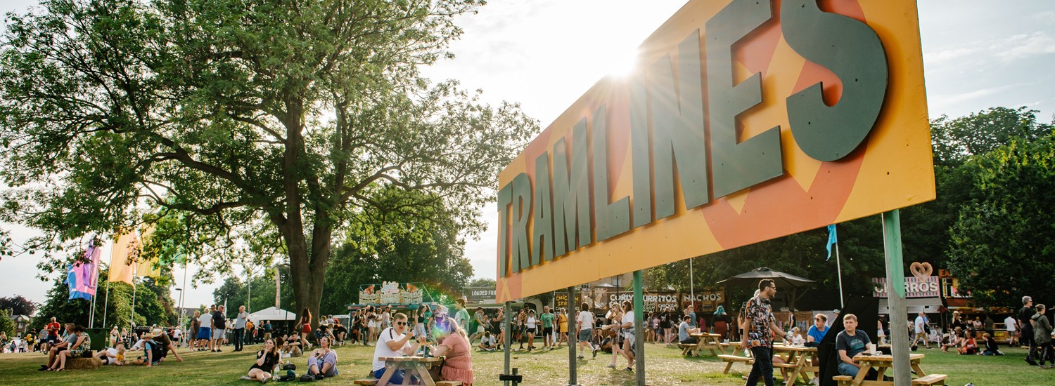 Tramlines sign with trees and people in background
