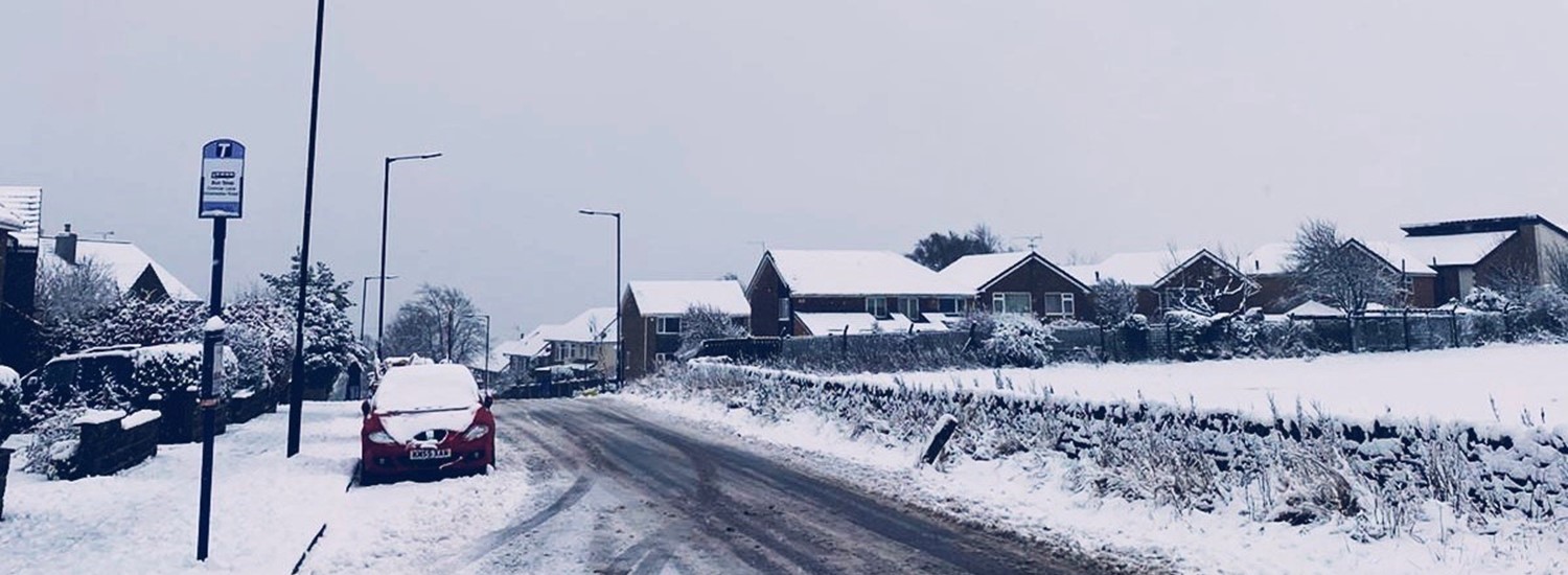 Snow on the road with a parked car under a lamp post