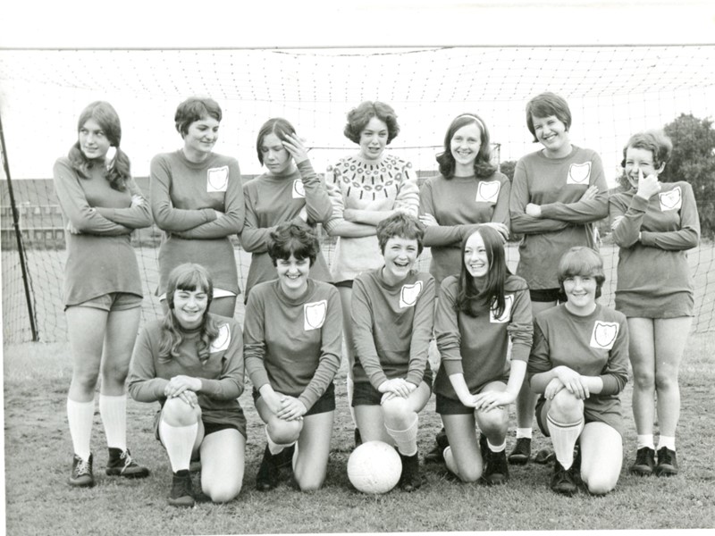 women's football team standing by goal posts