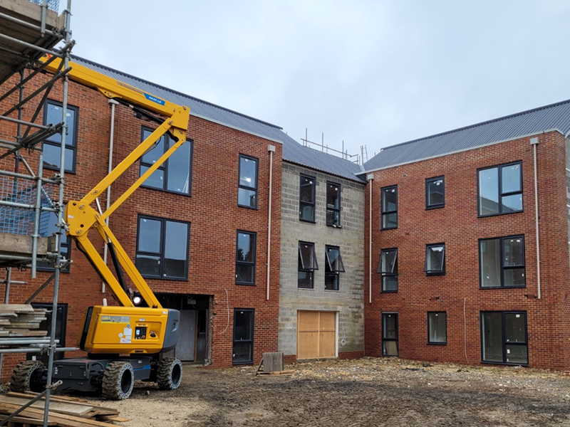 Red brick buildings under construction with scaffolding and a crane
