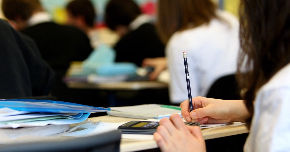 Pupil at a desk in school writing in a notebook