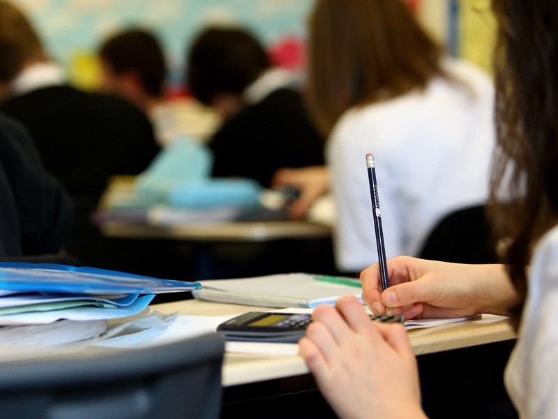 Pupil at a desk in school writing in a notebook