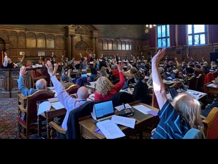 Councillors in the council chamber, raising their hands, unanimously approving the new committee system