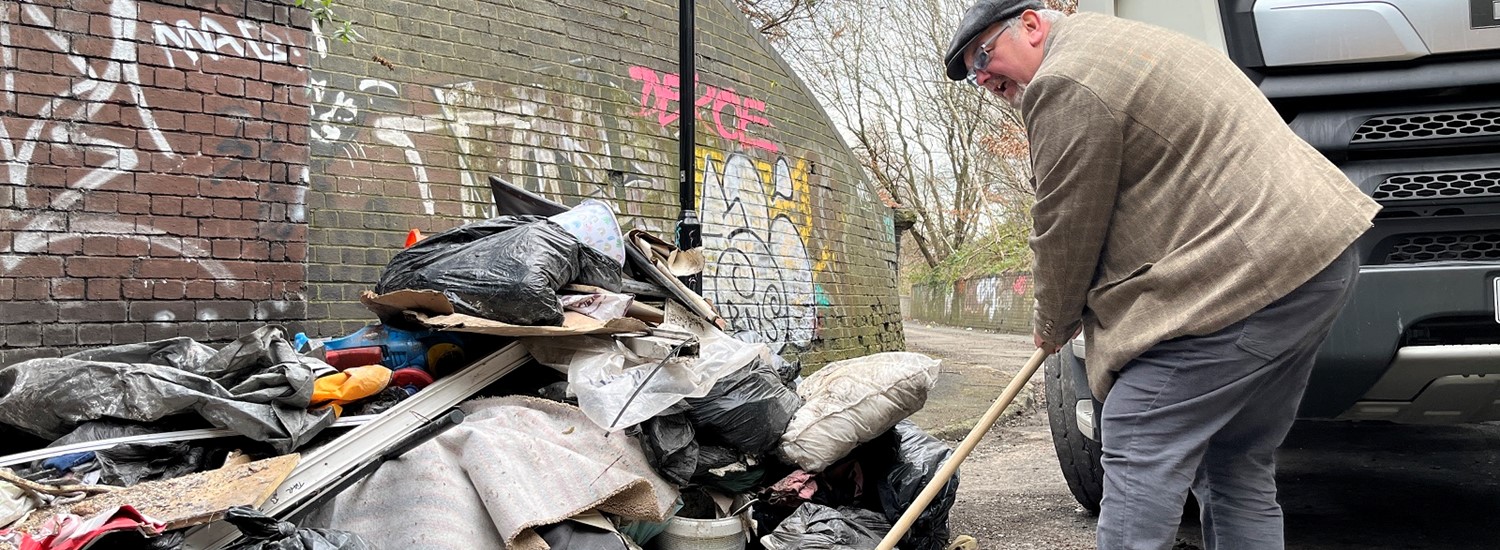 Councillor Terry Fox shovelling flytipped waste at Colliery Road in Sheffield