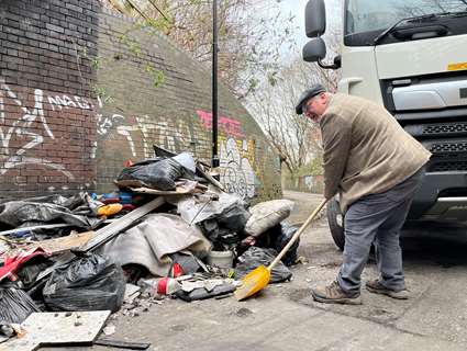 Councillor Terry Fox shovelling flytipped waste at Colliery Road in Sheffield