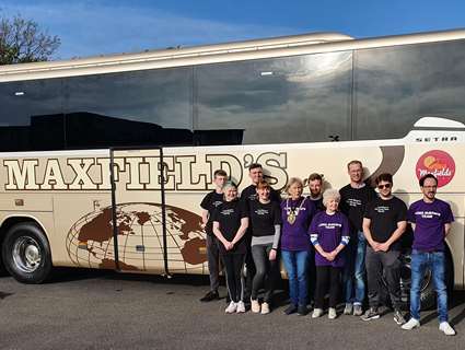 Gail Smith centre of photo in purple t shirt and her friends and volunteers standing in front of the Maxfield's coach