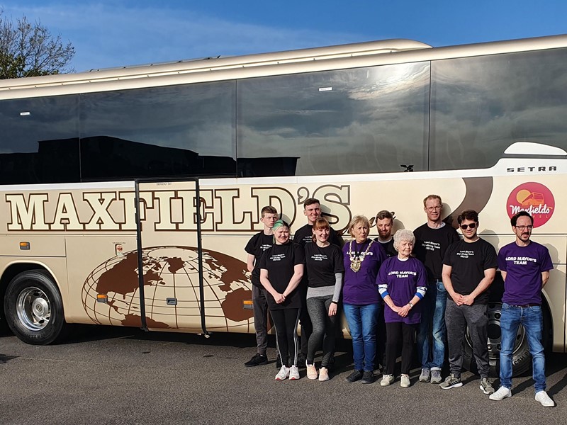Gail Smith centre of photo in purple t shirt and her friends and volunteers standing in front of the Maxfield's coach
