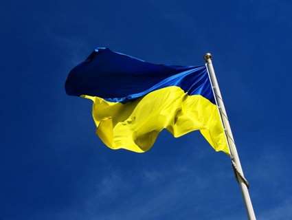 Blue and yellow Ukrainian flag on white pole with blue background