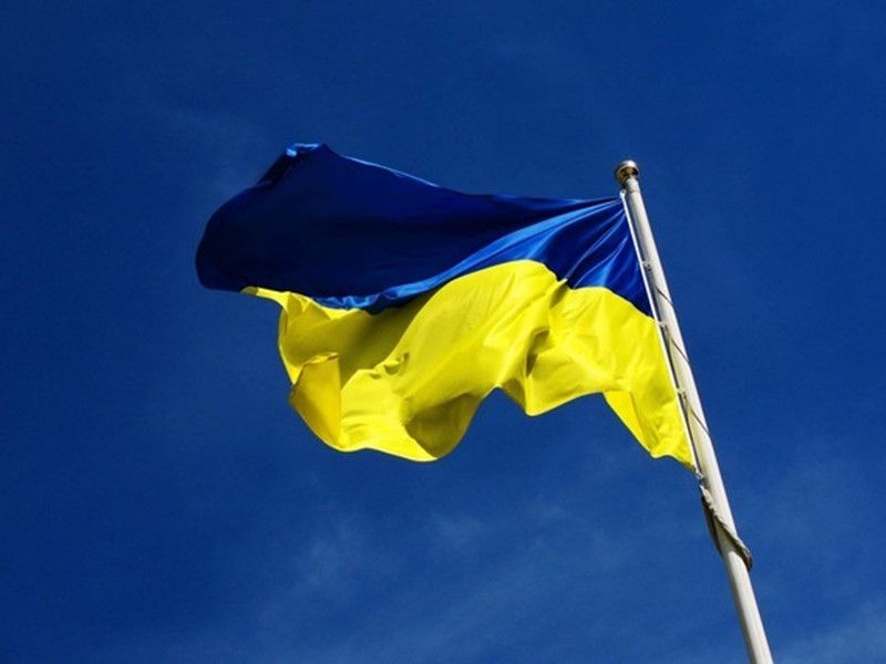 Blue and yellow Ukrainian flag on white pole with blue background