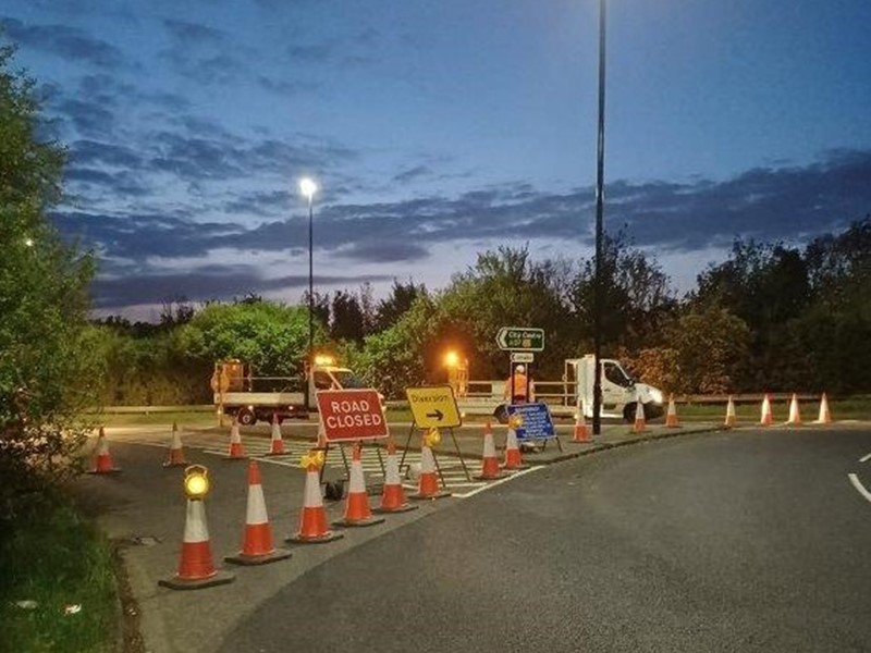 Cones and road closed sign on road next to street light