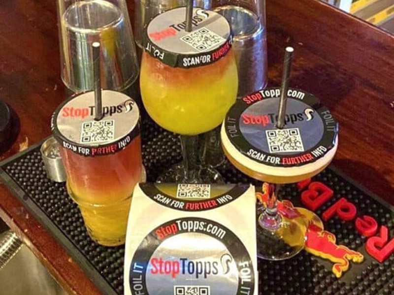 Drinking glasses with straws on a bar with secure toppers