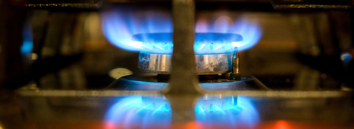 A close up of a blue flame lit on a gas ring hob