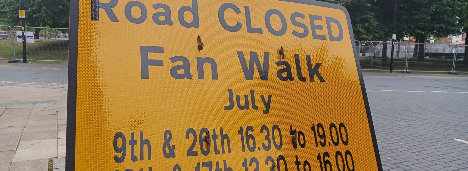 A yellow sign that says Road Closed Fan Walk with times of closures
