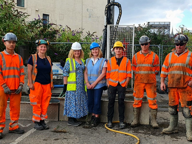 Archaeologists in orange hi-vis clothing stand in front of a borehole drill with Principle Development Officer Ruth Masoon and Cllr Julie Grocutt