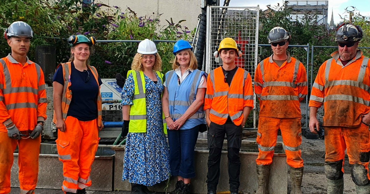 Archaeologists in orange hi-vis clothing stand in front of a borehole drill with Principle Development Officer Ruth Masoon and Cllr Julie Grocutt