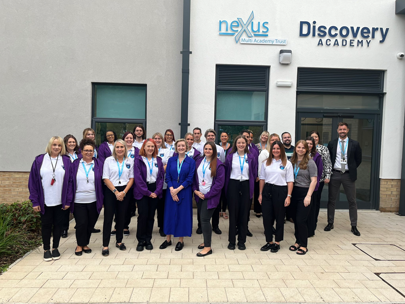 Teachers and staff at the Discovery Academy standing in front of the entrance to the school.