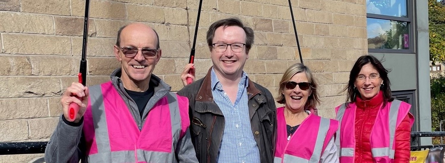 Four people holding litter pickers stood in front of library