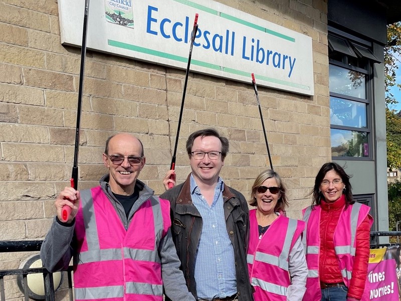 Four people holding litter pickers stood in front of library