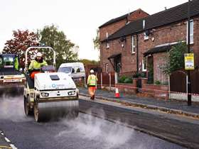 A tarmac roller with steam coming from the floor