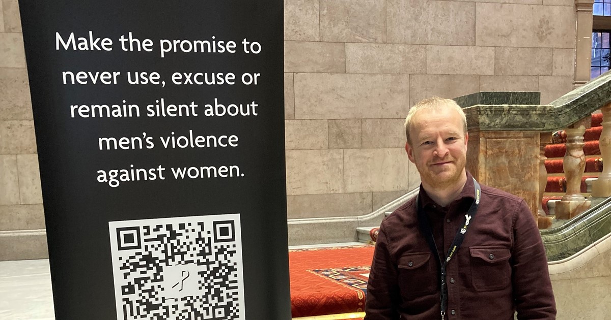 White Ribbon banner in town hall with Tom Smith standing next to it